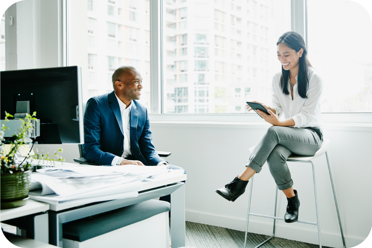 Two business people sitting in an office smiling