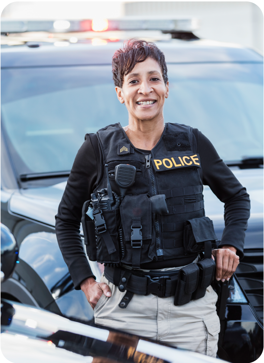 A smiling police woman standing in front of a police car