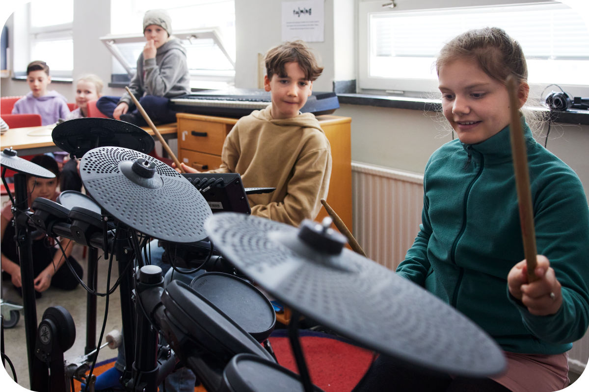 Children in a band room while two children are playing electronic drums