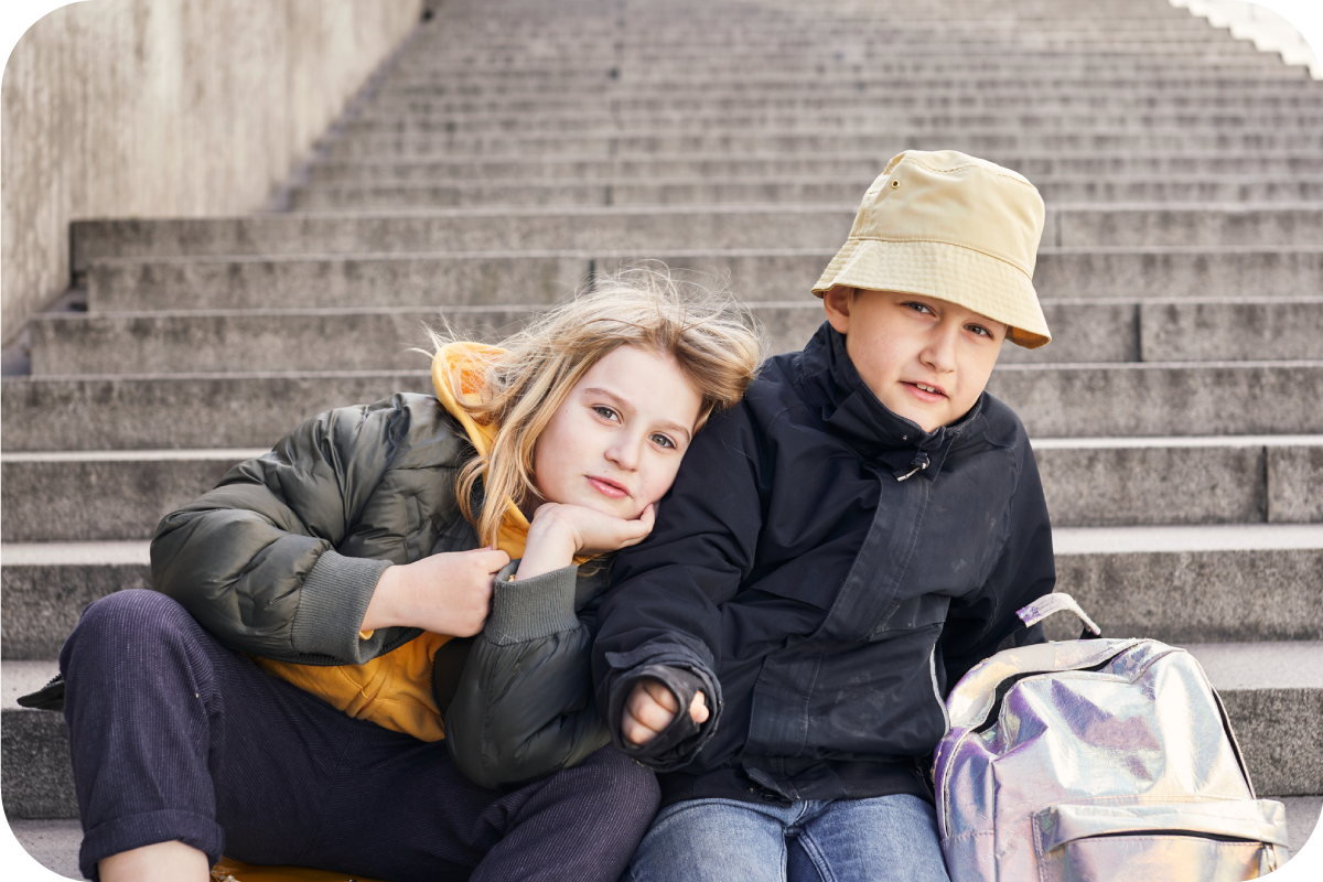 Two children sitting on steps where one child is leaning on the other
