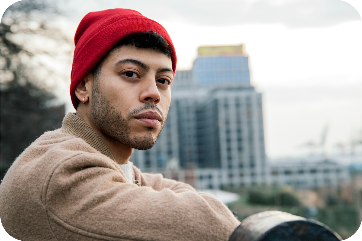 A man in a red hat is outside and looking off into the distance.
