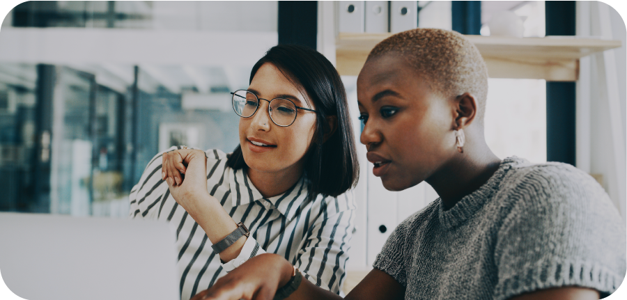 Two young business women are having a discussion while looking at a computer screen.