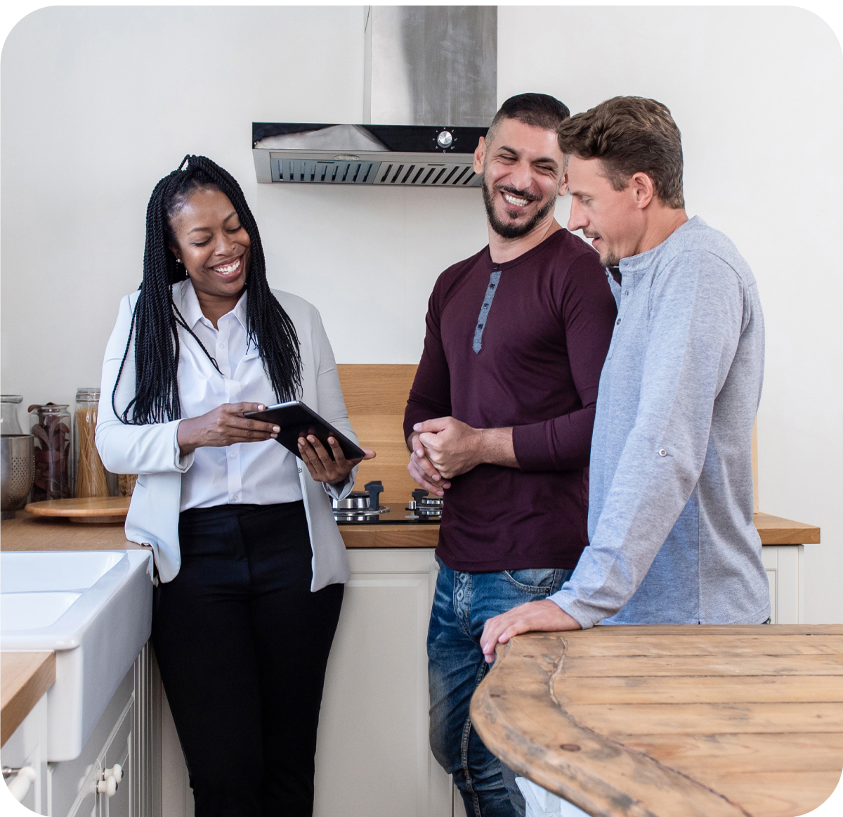 A young couple are chatting in the kitchen with a realtor at their new home.