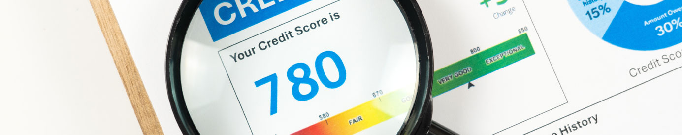 A credit report clipped onto a clipboard with a magnifying glass laying over the score portion, showing the score “780”.
