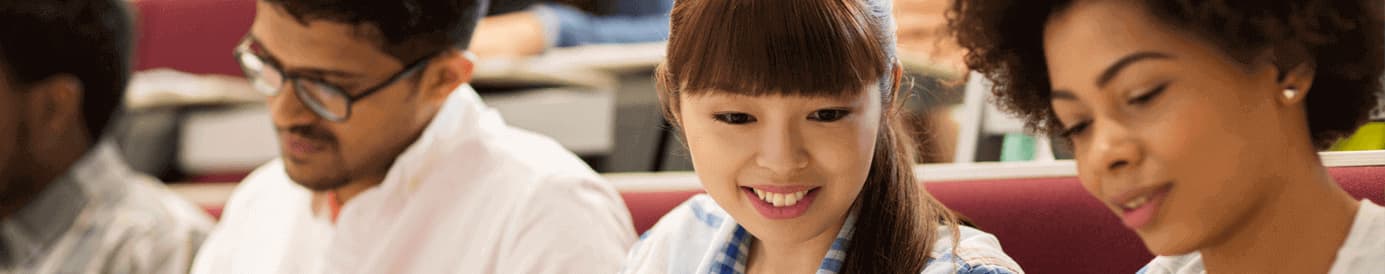 Two women look down and smile while a man in the background looks focused