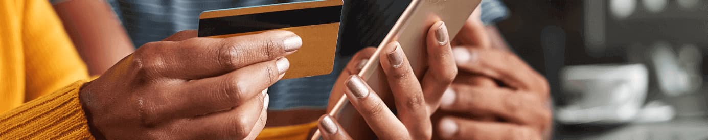 A woman holding a cellphone in her left hand and a credit card in her right hand