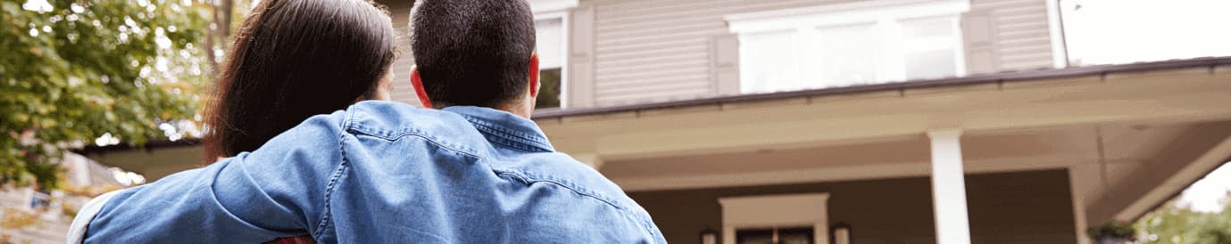 A man embraces a woman in front of a house