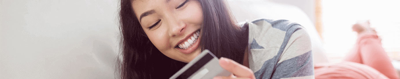 A woman looking down at a credit card and smiling