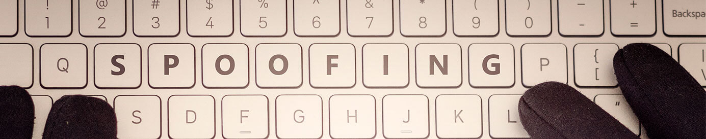 Two hands in black gloves sit on a keyboard with the word 'spoofing' centered on the third row of keys.