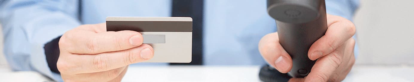 A man holding a credit card with his right hand while holding a phone receiver with his left hand