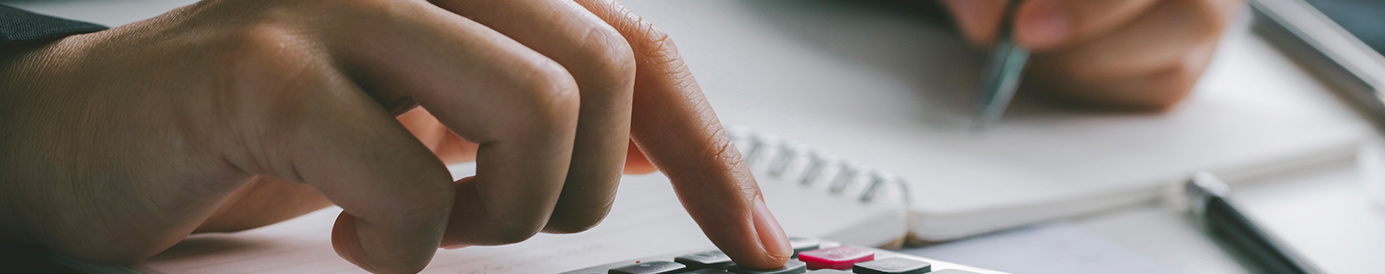 A person calculating their debt to income ratio with a pen and calculator