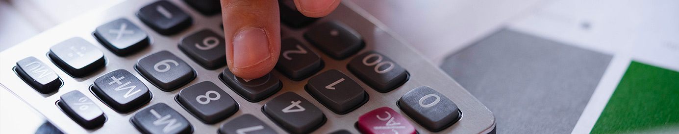 A person holding a pencil while typing into a calculator