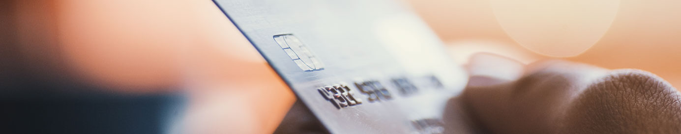 A photo of a person’s hand, holding a credit card