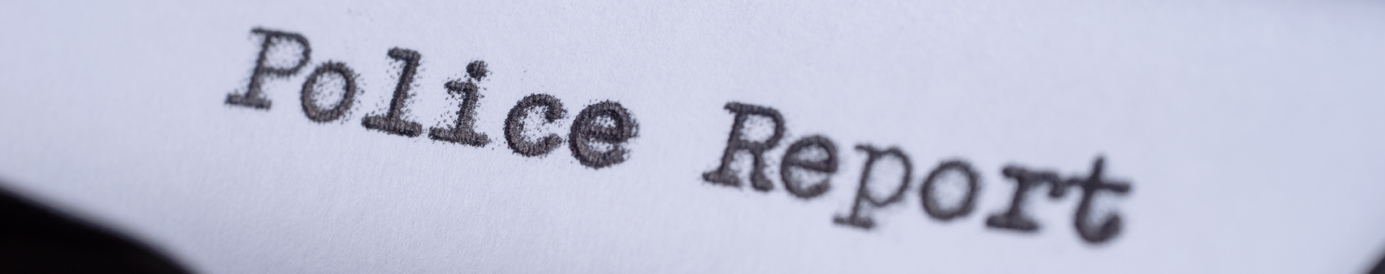 Close-up view of a vintage typewriter with the words “police report” typed out on the page in black ink.