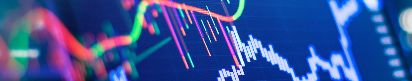 A side-angled view of a computer screen with red and green chart data showing stock market and trading information.