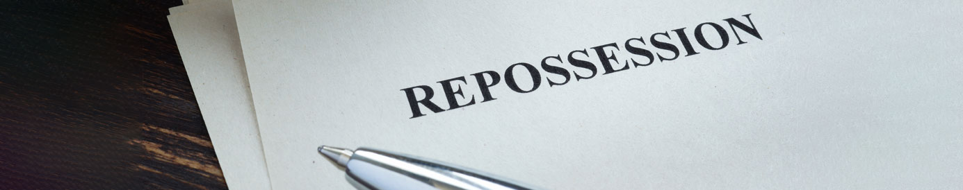 A document rests on a wood surface with the title 'REPOSSESSION'. The tip of a ballpoint pen is visible next to the copy.