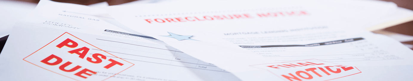 Papers scattered on a table with PAST DUE, FINAL NOTICE, and FORECLOSURE stamped on them