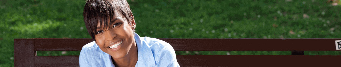 A woman sitting on a bench in a park smiles