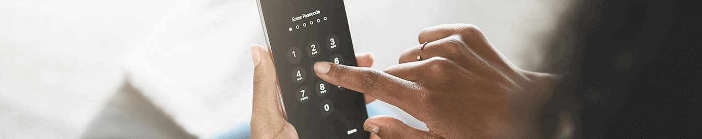 A person holds a cellphone with their left hand while their right hand enters a six-digit passcode into their cellphone