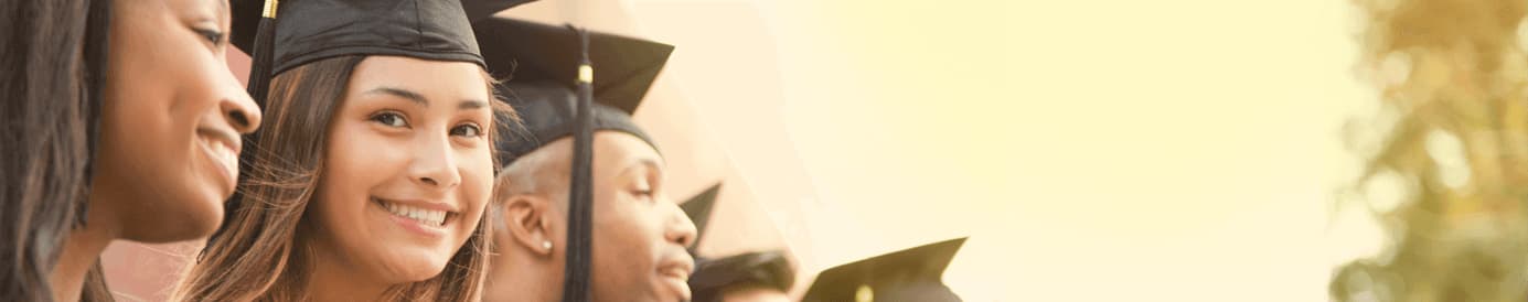 Three graduates standing next to each other and smiling with two additional graduation caps in the background