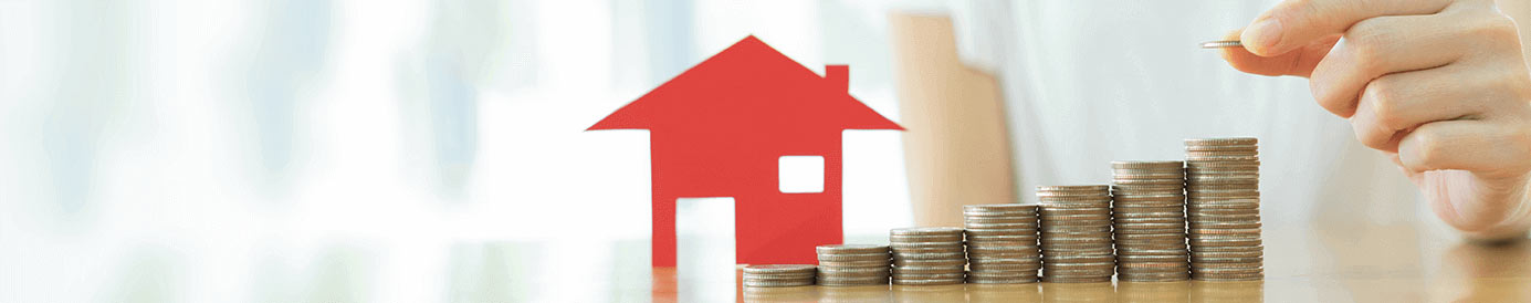 A person stacking coins into a step formation in front of a little red house cutout