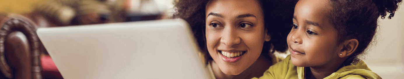 A woman and a young girl smiling at a laptop screen
