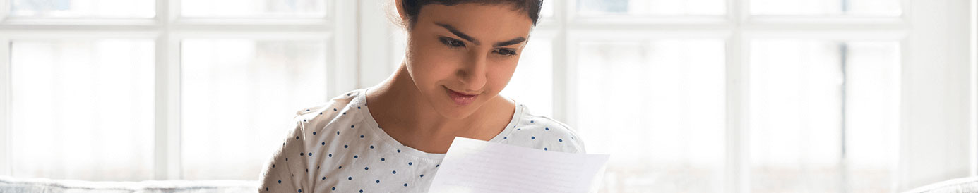 A woman holds a piece of paper with both hands and stares at it