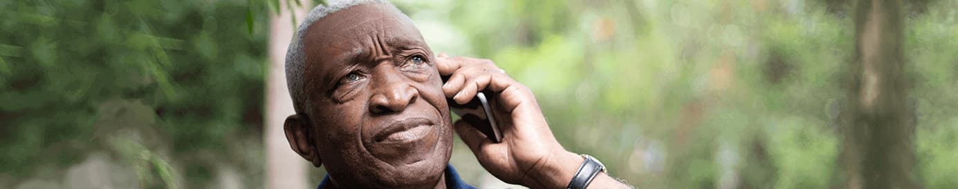A serious looking man holding a cellphone to his left ear