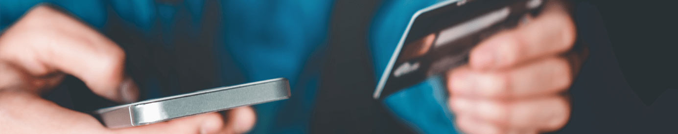 A person holding a credit car in their left hand and a cellphone in their right hand