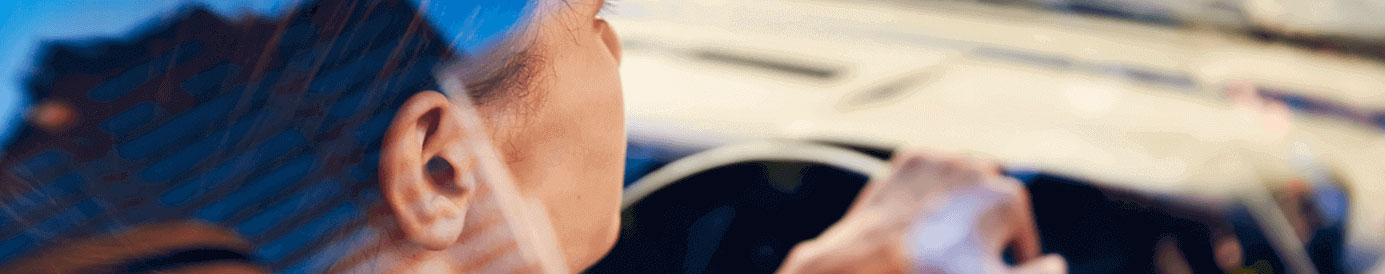 A woman driving a car, she is making a right turn.