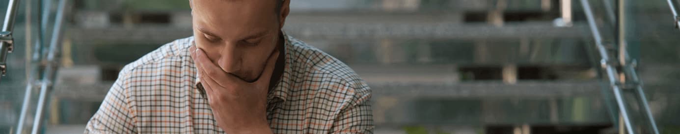 A man focusing while writing in a notebook on his lap