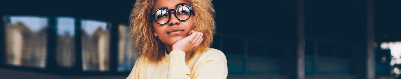 A woman with glasses looks up while writing in a book