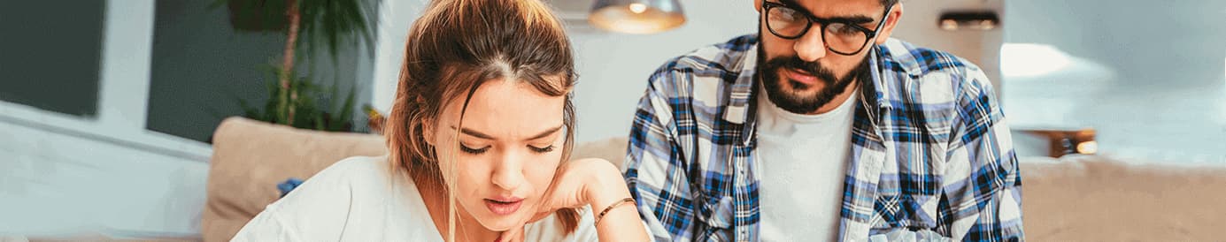 A woman and a man both look down and study something intently