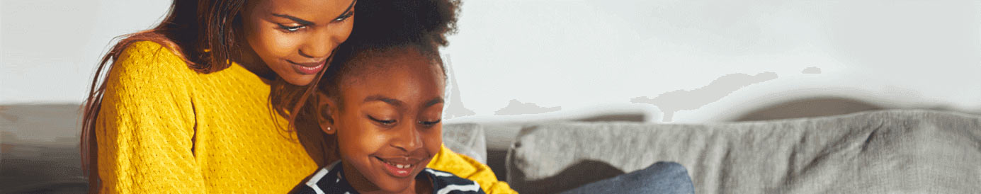 A woman and a young girl looking down and smiling at a tablet