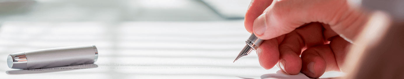 A person using a fountain pen to write something on a paper