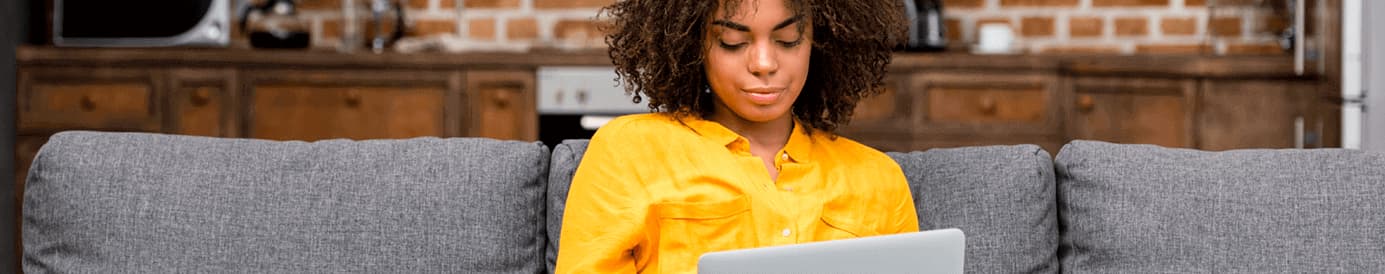 A woman sitting on a couch while looking at her laptop screen