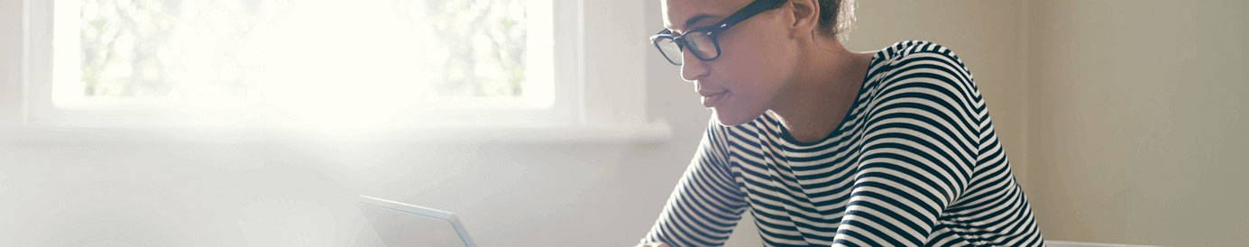 A woman wearing glasses looks down at a screen