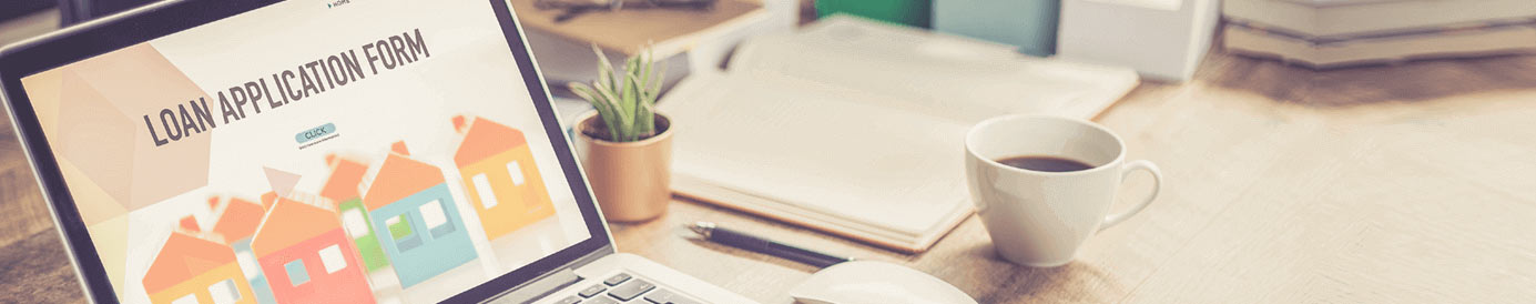 An opened laptop showing a loan application page on the screen with a succulent, notebook, pen, and white coffee mug on the table beside the laptop