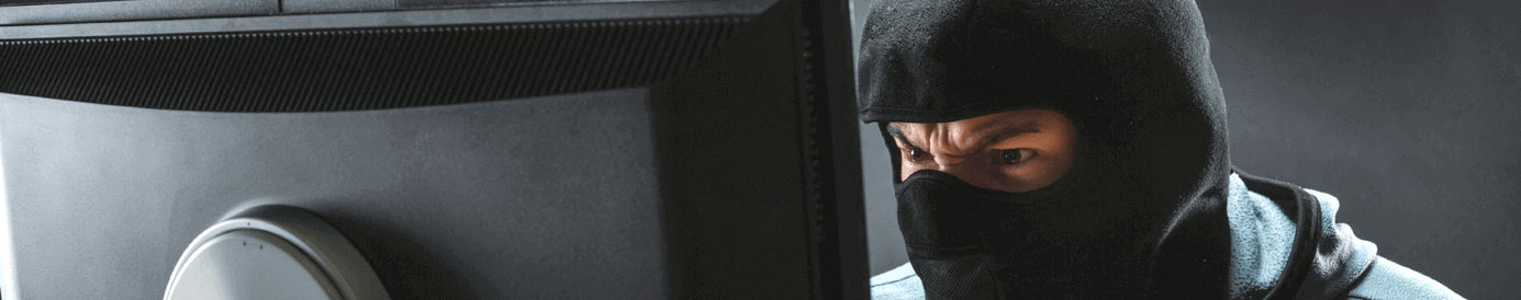 A man in a ski mask angrily looking at a computer screen