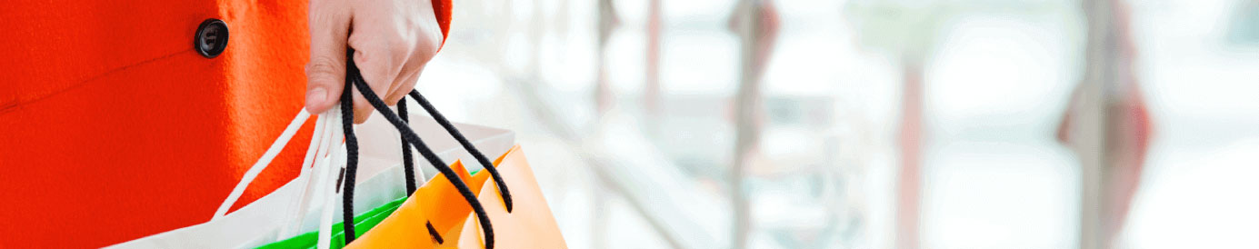 A person holds white, green, and orange shopping bags