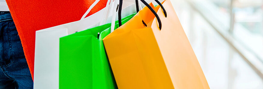 A white shopping bag, a green shopping bag, and an orange shopping bag