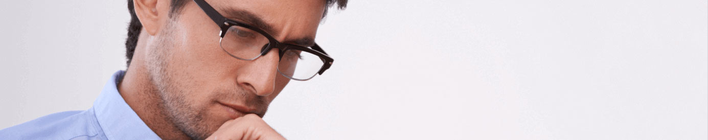 A man wearing glasses looks down while resting his chin on his left hand