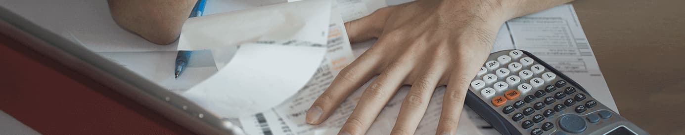 A person using their left hand to hold several receipts down