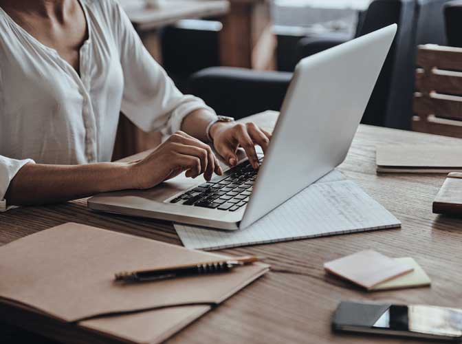 woman at a table typing on her computer