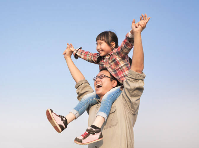 Man carrying a child on his shoulders and they are both laughing