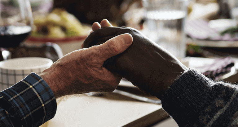 Two people holding each others' hand at a meal