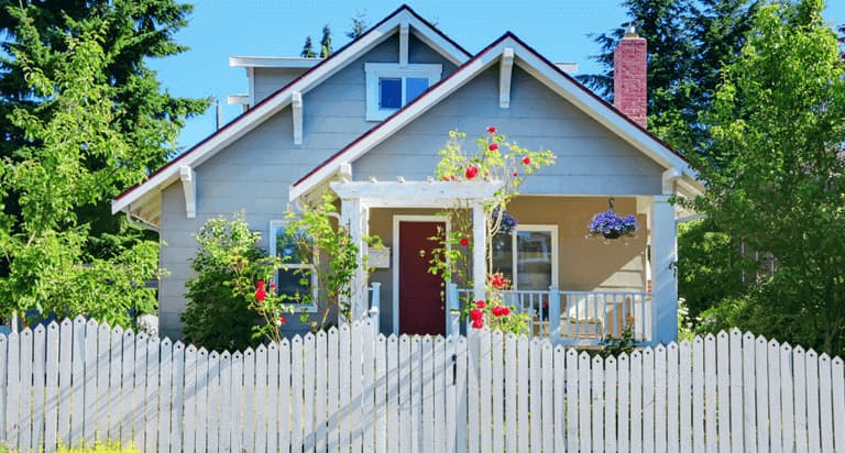 A white picket fence in front of a small house