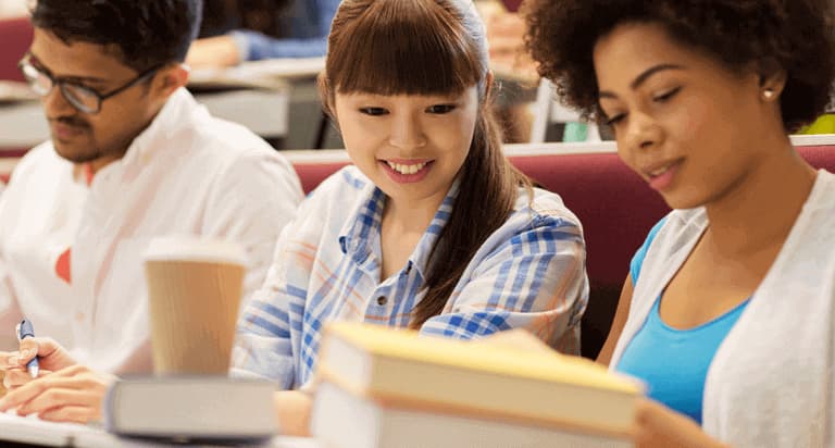 Two women look down and smile while a man in the background looks focused