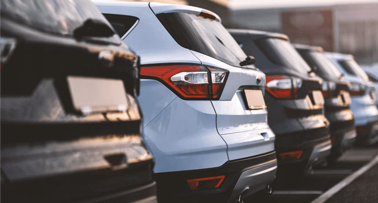 A line of cars parked in a car dealership parking lot