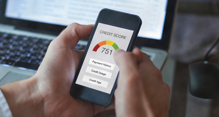 Hands hold a mobile phone with a credit app open. The header reads “Credit Score” followed by a score gauge that reads “751”.